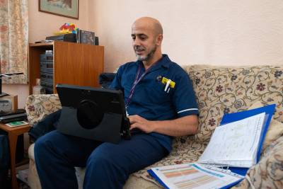 Community Nurse using mobile working unit at patient's home.